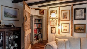 A cozy room with a bookshelf, a sofa, and framed pictures on the wall. - Host & Stay | Wistermead Cottage (Dolton)
