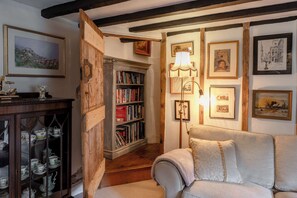 Ein gemütliches Zimmer mit Bücherregal, einer Couch und gerahmten Bildern an der Wand.