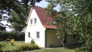 A two-story house with a red-tiled roof, a small attached garage, and a well-maintained lawn. - Ferienhaus in Püttsee auf Fehmarn (Püttsee)