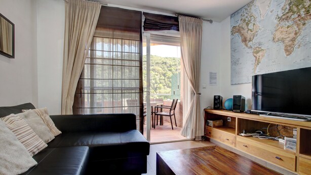 A living room with a black sofa, wooden coffee table, TV, speakers, and a world map on the wall. - Two-Bedroom Benahavis Village Apartment with beautiful Mountain View. (Benahavís)