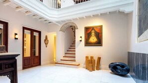 Un vestíbulo espacioso con una escalera, un cuadro grande enmarco y una escultura moderna.