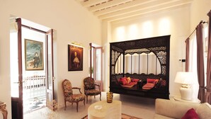 Amplia sala de estar con sofá, sillones, un separador decorativo y vistas al exterior.