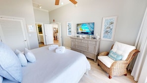 Ein Schlafzimmer mit einem Bett, einem Fernseher, einem Korbsessel und einem Schrank.