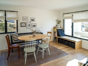 A dining area with a round wooden table, two chairs, a bench, and a window with curtains. - Abitaziun Patgific - Ferienwohnung im Casa Hirundella, (Trin Mulin), by Interhome (Trin)