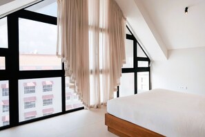 A bedroom with a large window, a bed, and a view of buildings outside. - Majestic 2-Bed Balcony City View Loft Suite by Bocobay (Willemstad)