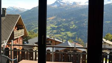 Une vue sur la montagne depuis un balcon, avec un chalet en bois et une chaise.