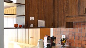 Een keuken met houten kastjes, een fornuis, een koffiezetapparaat en een vaatwasser.
