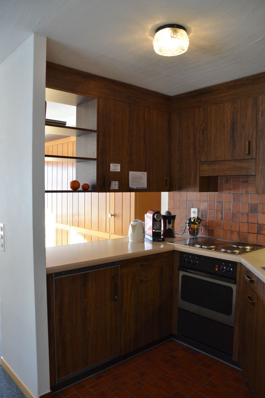 Une cuisine avec des meubles de rangement en bois, une machine à café, une bouilloire et une cuisinière.