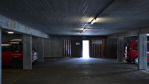 Een parkeergarage met betonnen pilaren, een rode auto en een bord dat aangeeft dat er een helling is.