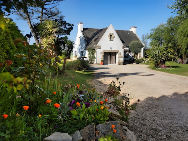 A house with a stone facade, a large front door, and a driveway leading to it.