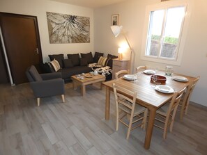 Ein Wohnzimmer mit einer Couch, einem Couchtisch und einem Esstisch für vier Personen.