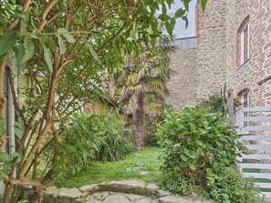 A stone building with a white fence, lush greenery, and a stone pathway. - 400 m from the beach, apartment for 2 (Dinard)