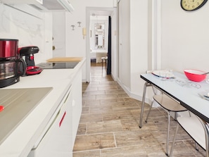 A kitchen with a coffee maker, a red bowl, and a dining table with chairs. - 400 m from the beach, apartment for 2 (Dinard)