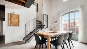 A dining area with a wooden table, black chairs, a modern lamp, and a staircase. - w* | Luxury 5BR Retreat near Navigli (Milano)
