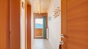 Un pasillo con puertas de madera, vistas a un balcón y suelo de baldosas.