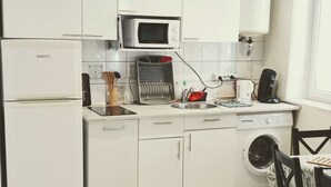 A compact kitchen with a refrigerator, microwave, sink, and a small dining area with a chair. - Historic district of Agde (Agde)