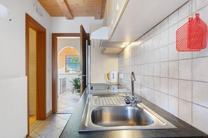 Eine moderne Küche mit Spüle aus Edelstahl, einer Kaffeemaschine und einem roten Hängegestell.
