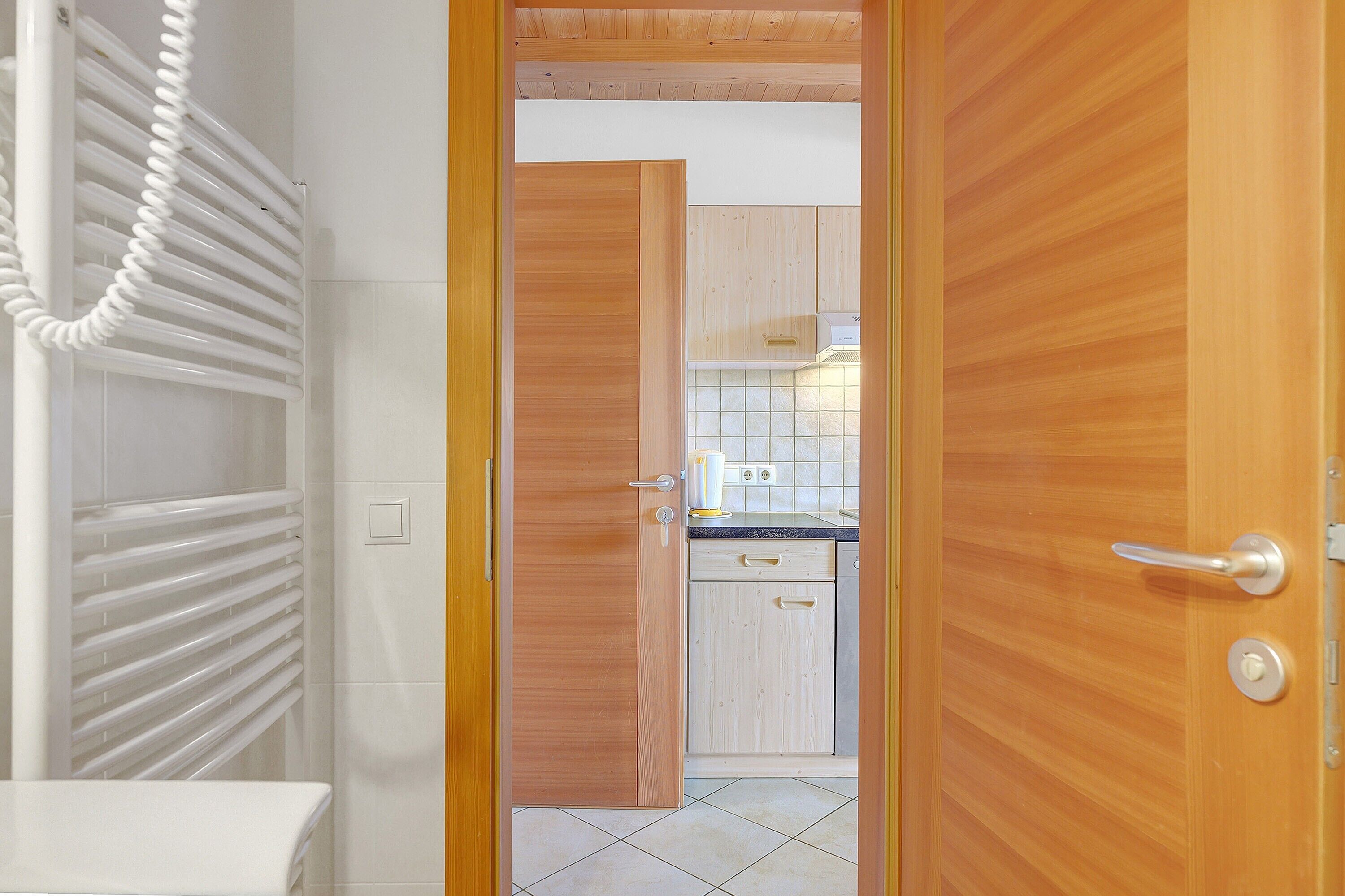Una porta in legno che dà su una cucina con armadietti, un piano di lavoro e un porta asciugamani.