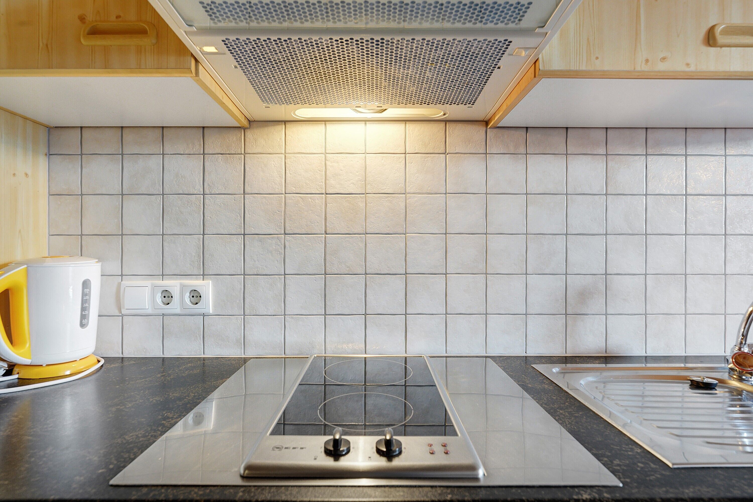 Een keuken met een moderne inductiekookplaat, een ingebouwde oven en een roestvrijstalen spoelbak.