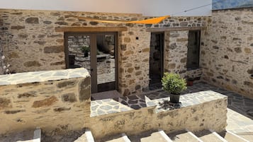 A stone building with a balcony, a potted plant, and a view of mountains.