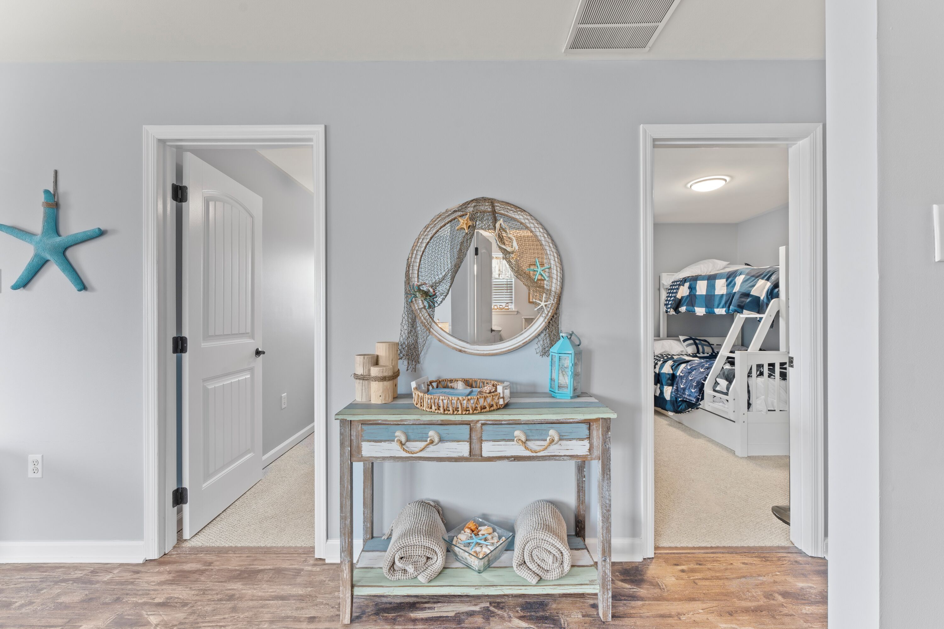 A hallway with a console table, a mirror, and a starfish decoration.