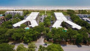 Un hotel costero con varias edificaciones, estacionamiento y vista a la playa.