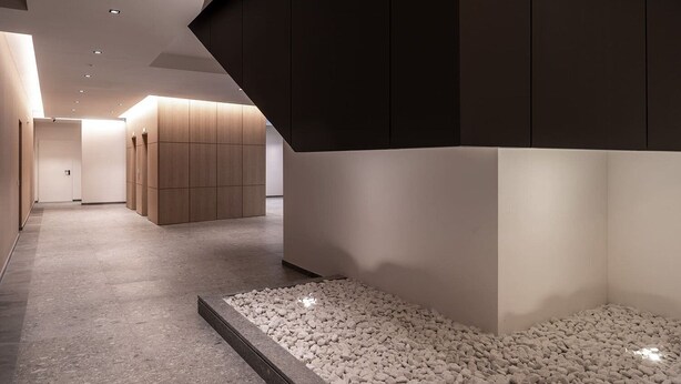 Een modern interieur met een gang, een zithoek met stenen vloer en een houten paneelwand.