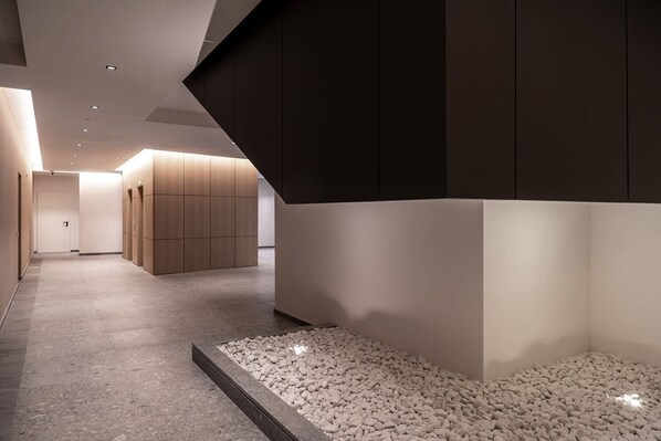 Ein modernes Interieur mit einer Diele, einer Sitzecke mit Steinboden und einer Wand aus Holzverkleidung.