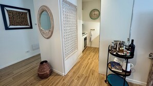 Een modern interieur met een houten vloer, een decoratieve spiegel, een behang met patroon, een klok en een plank met diverse objecten.