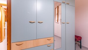 Une armoire à plusieurs portes et tiroirs, un miroir et une chaise rouge dans une pièce aux murs de couleur claire.