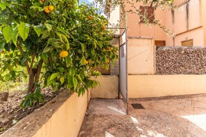 A courtyard with a lemon tree, a metal gate, and a stone wall. - Posada apartment a few minutes from the sea (Posada)