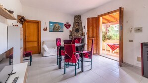 Un coin repas avec une cheminée en pierre, un canapé et une table avec des chaises.