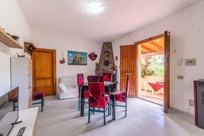 A dining area with a stone fireplace, a sofa, and a table with chairs. - Posada apartment a few minutes from the sea (Posada)