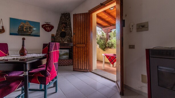 Une pièce avec une cheminée, une table à manger avec des chaises, un téléviseur et une vue sur l’extérieur.