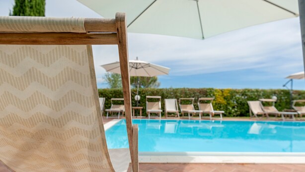 A poolside area with lounge chairs and umbrellas. - Poggio Novello - Agriturismo Peccioli (Peccioli)