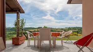 An outdoor patio with a table and chairs, a potted plant, and a view of the countryside. - Poggio Novello - Agriturismo Peccioli (Peccioli)