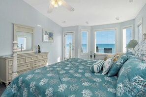 Ein Schlafzimmer mit Bett, Schminktisch und Fenstern mit Blick aufs Meer.