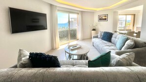 Un salon moderne doté d’un téléviseur à écran plat, d’un canapé, d’une table basse et d’un balcon offrant une vue agréable.