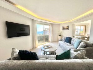 Ein modernes Wohnzimmer mit Fernseher, einer Couch, einem Couchtisch und einem Balkon mit Blick.