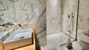 Une salle de bain moderne avec un lavabo en marbre, une cabine de douche en verre et un meuble-lavabo en bois.