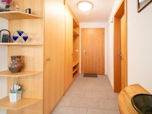 A hallway with wooden doors, shelves with decorative items, and a tiled floor. - Crap Uaul by Interhome (Flims)