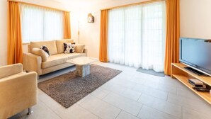 A modern living room with a sofa, coffee table, TV, and large windows with curtains. - Crap Uaul by Interhome (Flims)
