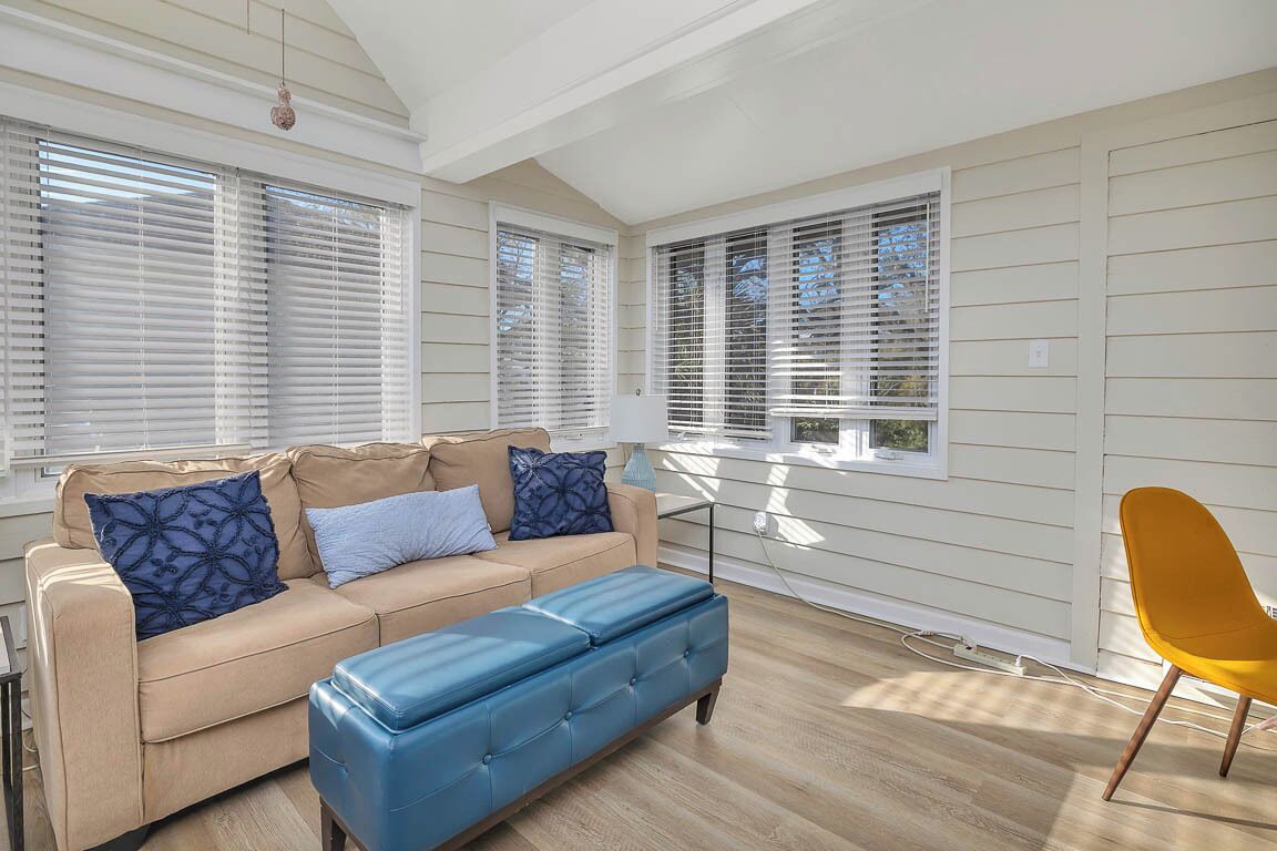 A room with a beige sofa, blue ottoman, and a yellow chair.