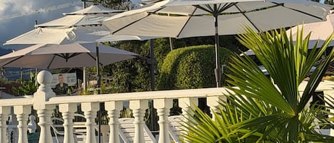 A balcony with white railings and multiple white umbrellas.