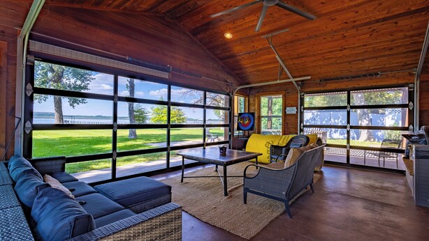 A spacious room with large windows, a ceiling fan, and a dining area. - Never a Bad Day at PK Lake- Waterfront, Pool Table, Firepit (Graford)