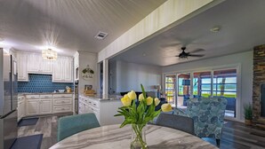 A modern kitchen with white cabinets, a blue backsplash, and a dining area with a marble table and a vase of yellow flowers. - Never a Bad Day at PK Lake- Waterfront, Pool Table, Firepit (Graford)