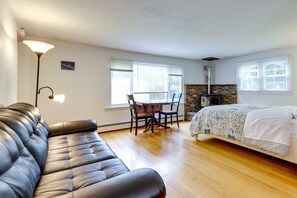 A bedroom with a bed, a sofa, a dining table with chairs, and a fireplace.
