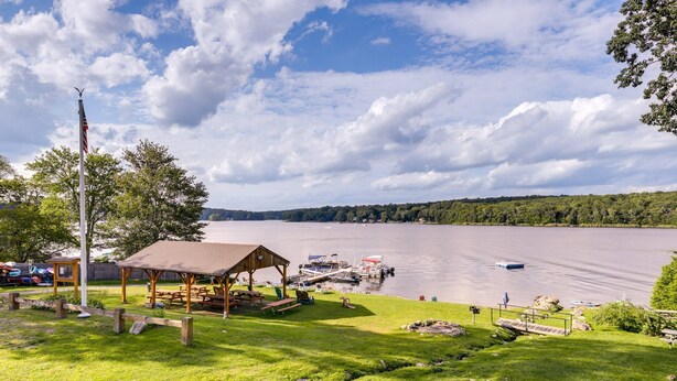 Un parc au bord du lac, équipé de tables de pique-nique, d’un pavillon abrité et d’un quai avec des bateaux.