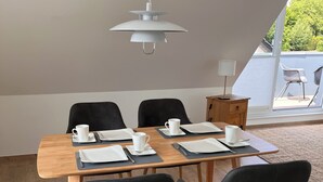 Zona pranzo con tavolo in legno, sedie nere e lampadario.