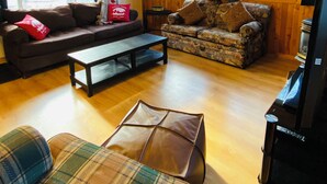 A cozy living room with wooden walls and floors, two sofas, a coffee table, and a television. - Blue Moon Retreat (Combermere)